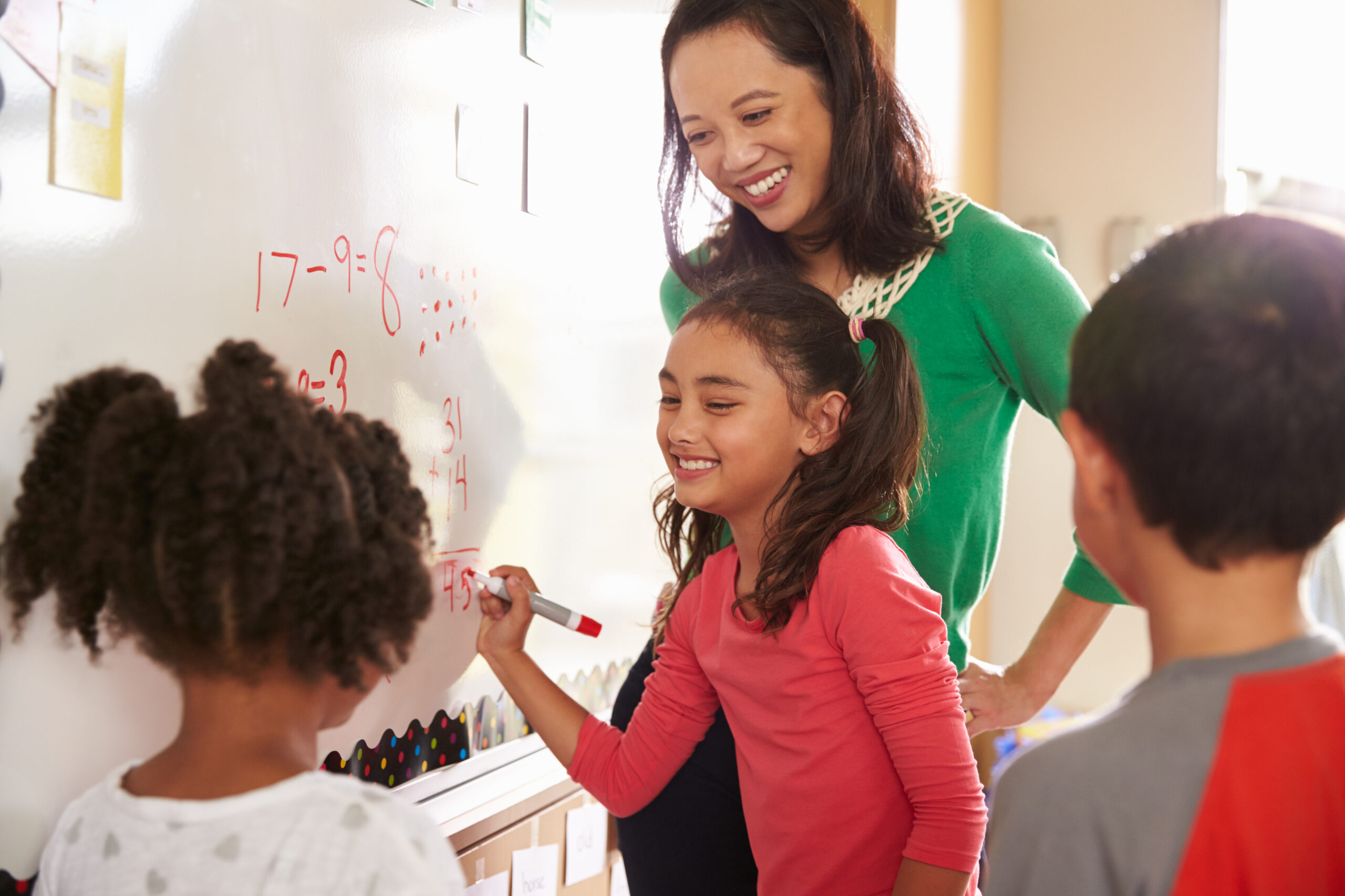 Pupil writing on the board at elementary school maths class