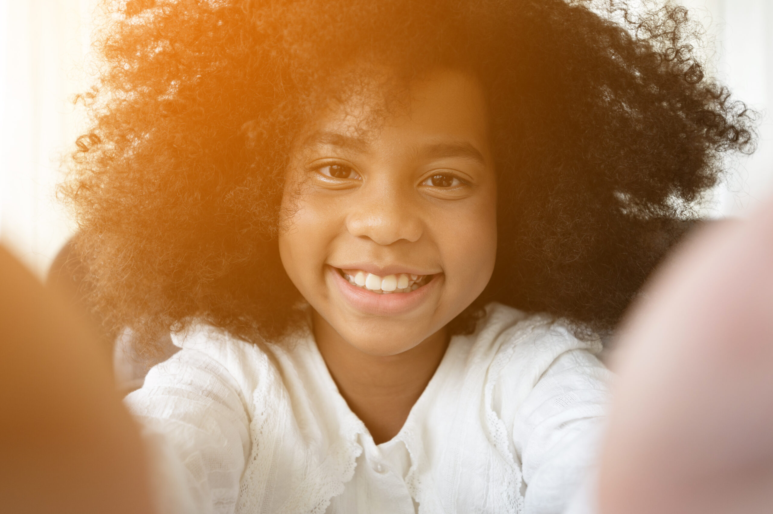 Selfie portrait of laughing black African American girl outside with curly hair