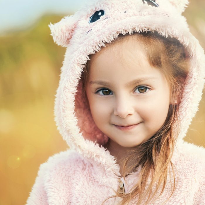Close-up portrait of a charming brown-eyed five-year-old girl walking on a street on a warm summer evening. The concept of naive children