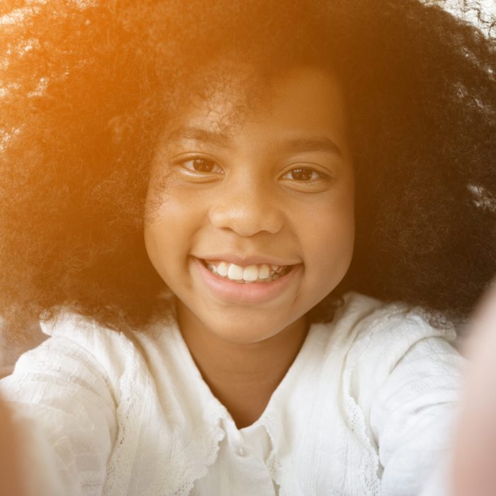 Selfie portrait of laughing black African American girl outside with curly hair